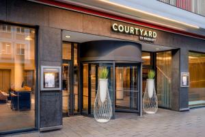 two vases with plants in them outside of a building at Courtyard by Marriott Munich City Center in Munich