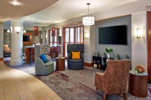 a lobby with chairs and a living room with a tv at Courtyard Rochester Brighton in Rochester