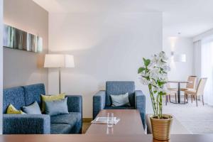 a living room with two blue chairs and a table at Courtyard by Marriott Munich City Center in Munich