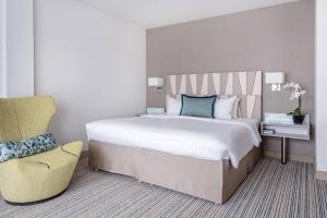 a bedroom with a large bed and a chair at Courtyard by Marriott Munich City Center in Munich