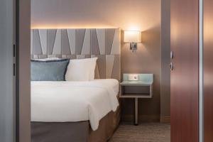 a bedroom with a bed and a table with a lamp at Courtyard by Marriott Munich City Center in Munich