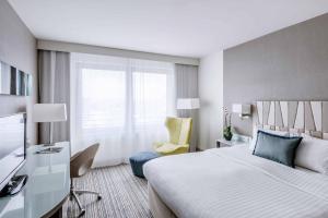 a hotel room with a bed and a chair at Courtyard by Marriott Munich City Center in Munich