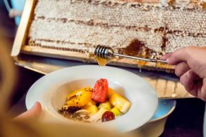 a person is holding a bowl of food with a honey bottle at Courtyard by Marriott Munich City Center in Munich