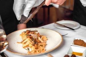 a person holding a utensil over a plate of pasta at Courtyard by Marriott Munich City Center in Munich