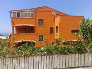 an orange house sitting behind a fence at B&B Figli Dei Fiori in Realmonte