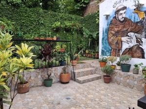 a garden with potted plants and a mural of a man at Casa avemaría in Cali