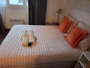 a bed with two towels on it with orange pillows at Grain de sable ! terrasse en ville in Le Touquet-Paris-Plage