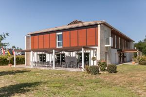 un edificio con una fachada de naranja en un campo en Hotel Alienor, en Langon