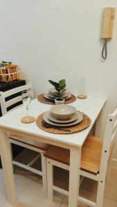 a white table with plates and glasses and a plant on it at Le Studio Serein de Jean-Mathïs in Manila