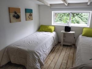 two beds in a small room with a window at CASA del PEZ céntrica para 5 huespedes in La Plata