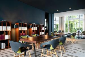 a library with two tables and chairs and bookshelves at Le Méridien Munich in Munich