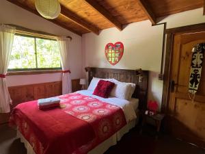 a bedroom with a bed with a red blanket at Cabañas Peumayen "La Panchita" in Huequecura