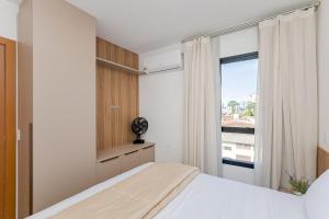 a bedroom with a bed and a window at Condomínio Niagara On The Lake | Gonzaga Stays in Curitiba