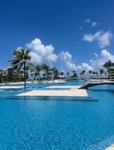 a large swimming pool with palm trees in the background at Mareazul Playa del Carmen in Playa del Carmen