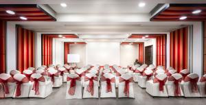 a room full of chairs in a room with red curtains at Regency Sameera Vellore by GRT Hotels in Vellore