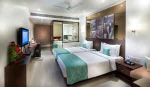 a hotel room with a large bed and a television at Regency Sameera Vellore by GRT Hotels in Vellore