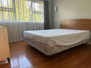 un letto in una camera con una grande finestra di Vale Whangārei a Whangarei