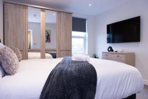 a bedroom with a white bed and a television at Lethbridge Villa 49 Apartment 2 Super Fibre WiFi, free parking in Southport