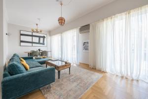 a living room with a blue couch and a table at Spacious 2BDs Apt With Acropolis View In Center in Athens