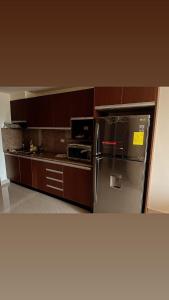 a kitchen with a stainless steel refrigerator and wooden cabinets at Suite en edificio Samborondon in SamborondÃ³n