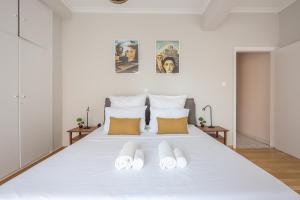 a white bed with two pairs of slippers on it at Spacious 2BDs Apt With Acropolis View In Center in Athens