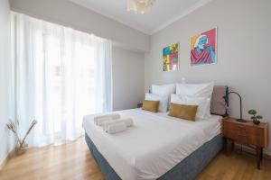 a bedroom with a large white bed with a window at Spacious 2BDs Apt With Acropolis View In Center in Athens