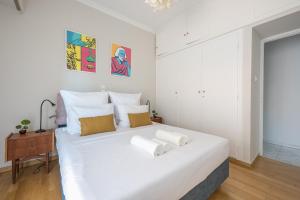 a white bedroom with a large white bed with pillows at Spacious 2BDs Apt With Acropolis View In Center in Athens