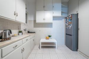 a kitchen with white cabinets and a black refrigerator at Spacious 2BDs Apt With Acropolis View In Center in Athens