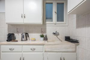 a kitchen with white cabinets and a sink at Spacious 2BDs Apt With Acropolis View In Center in Athens