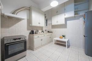 a kitchen with white cabinets and a stove top oven at Spacious 2BDs Apt With Acropolis View In Center in Athens