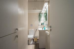 a white bathroom with a toilet and a sink at Spacious 2BDs Apt With Acropolis View In Center in Athens