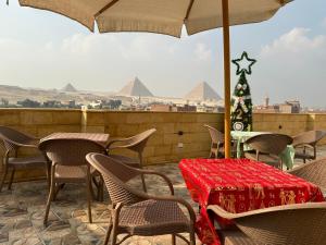 taras ze stołami, krzesłami i parasolem w obiekcie Hapi Pyramids Hotel w Kairze