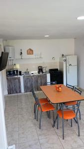 a kitchen with a wooden table and chairs and a kitchen with a refrigerator at Complejo Arenas in Pehuén-Có