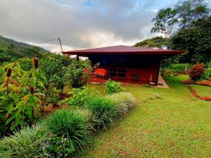 a small house with a red roof in a yard at Aloha chirripo cabaña familiar in Convento
