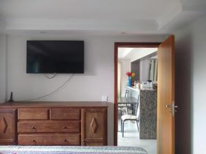 Una sala de estar con un televisor de pantalla plana en una pared. en Casa temporada, en Ilhabela