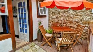 a wooden table and chairs with an umbrella on a patio at Casa Verde no Centro Histórico in Paraty