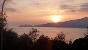 una puesta de sol sobre un gran cuerpo de agua con montañas en House Rouge by Holiday World, en Zoagli