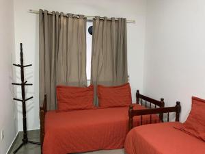 a bedroom with two beds with red sheets and a window at Casa Rebello - Pousada in Itajaí