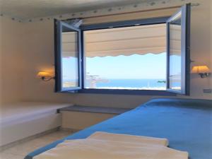 a bedroom with a window with a view of the ocean at Hermes Korifi Suites private apartment in Hersonissos