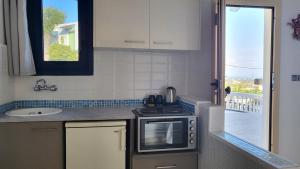 a kitchen with a stove and a sink and a window at Hermes Korifi Suites private apartment in Hersonissos