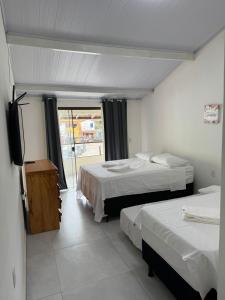 a hotel room with two beds and a television at Belas Praias Itacaré 2 in Itacaré
