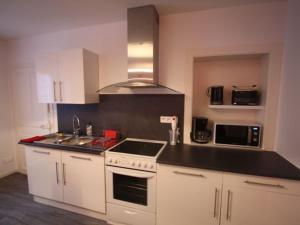 a kitchen with white cabinets and a black counter top at Appartement Rénové, Proche Centre-Ville Épinal, 2 Chambres, Confort, WiFi, Parking - FR-1-589-54 in Épinal