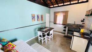 a living room with a table and a kitchen at Suítes e Chalé Colibri - Passarim Hospedagem in Cumuruxatiba +22 photos