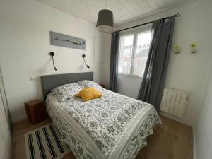 ein Schlafzimmer mit einem Bett mit einem gelben Kissen darauf in der Unterkunft Maison rénovée proche mer avec terrasse, parking privé et wifi à Barbâtre - FR-1-426-440 in Barbâtre