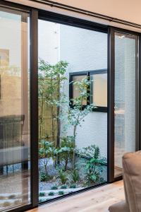 a room with a glass window with a garden outside at Apartment Hotel 11 Villa Hanazonocho in Osaka +43 photos