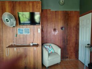 a room with a chair and a television and a fan at Surá House Corcovado SuriNico Room With AC in Puerto Jiménez