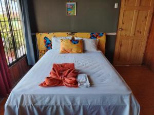 Una cama con sábanas blancas y un lazo encima. en Surá House Corcovado SuriNico Room With AC, en Puerto Jiménez