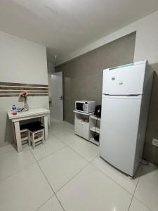 eine Küche mit einem Kühlschrank, einem Tisch und einer Mikrowelle in der Unterkunft Casa da margo in Florianópolis