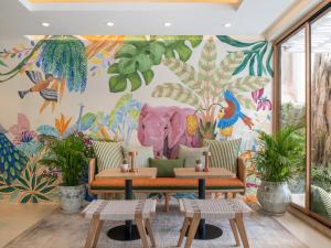 a mural in a room with tables and plants at Dusit Princess Chiang Mai in Chiang Mai