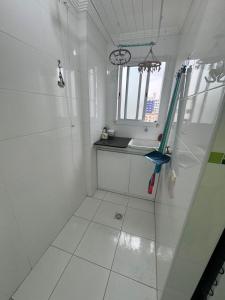 a white bathroom with a shower and a sink at Apto Novo Canto do Forte in Praia Grande